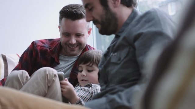 Same Sex Couple Family On The Couch Watching Digital Tablet