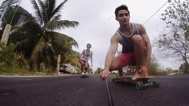 Man holding monopod and enjoying skateboarding with friend on street