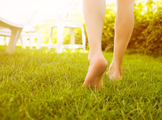 Close up female legs walking on the grass.