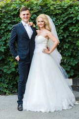 the bride and groom posing on the background of shrubs