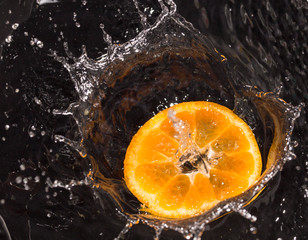 Fototapeta premium Orange in water splashes on a black background