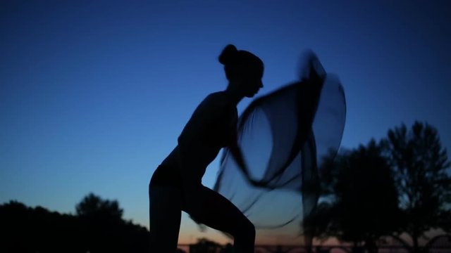 Sexy woman silhouette in twilight, girl with windy flying cloth