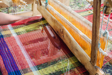 Weaving the threads on old wooden loom
