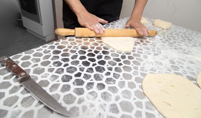 sheeting the dough with a rolling pin in the kitchen
