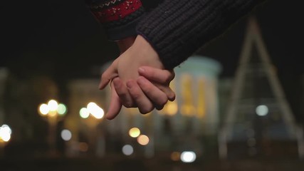 Young couple holding hands, interlocking fingers passionately, romantic date
