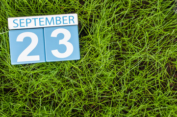 September 23rd. Image of september 23 wooden color calendar on green grass lawn background. Autumn day. Empty space for text