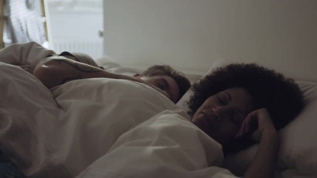 Mixed race couple cuddling in bed