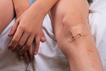 Child Pwith Band-Aid On His Knee. Kid with a plaster on his injured knee close up.