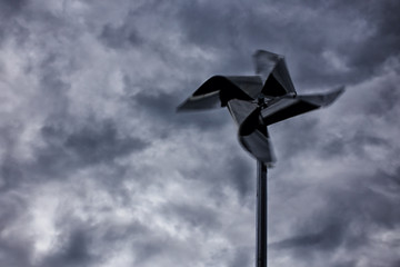 storm wind. metal toy pinwheel in rapid motion against the dark sky during a hurricane. non-flying weather. blurred motion. copy space for your text
