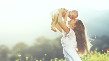 happy family outdoors. mother throws baby up, laughing and playi