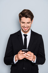 Happy man in black suit typing sms on smartphone