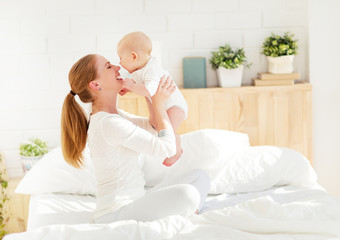 happy family mother  with baby playing and hug in bed
