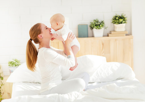 Happy Family Mother  With Baby Playing And Hug In Bed