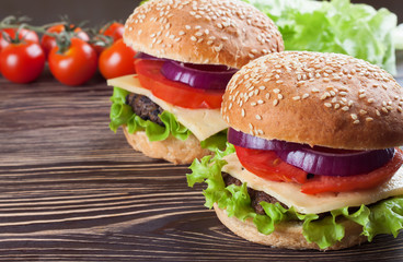 Homemade cheeseburger on brown wooden surface.