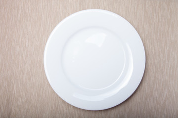 Empty white plate on grey napkin, top view