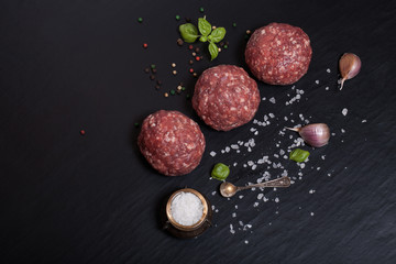 Raw ground beef meat steak cutlets with herbs and spices on blac