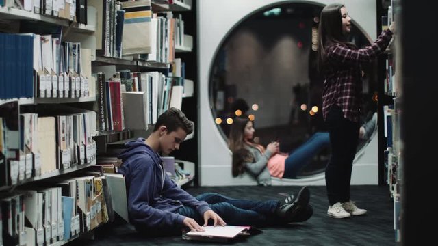 Teenage girls and boy studying in library