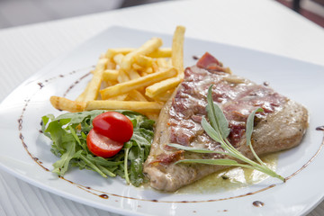 Pork steak in white plate and french fries .