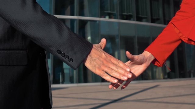 Slow motion. Cheerful businesspeople, or businesswoman and client handshaking. Manicure. Glass business centre building bg. red and black suit. steadicam close-up shooting