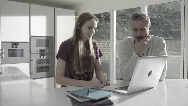 Mature adult male teaching teenage daughter in kitchen