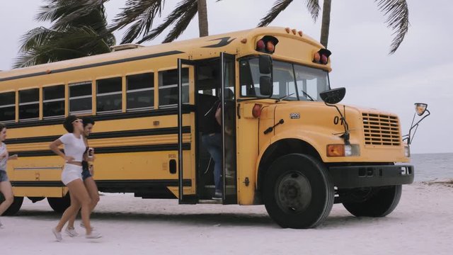 Friends enjoying and entering yellow bus at beach