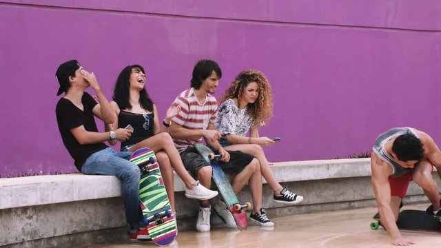 Friends sitting together and enjoying skateboarding on street