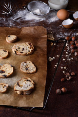 Baked bread rusks with raisins and nuts, cooking ingredients over rustic kitchen table. Brussels hazelnut biscuits, crispy appetizers. 