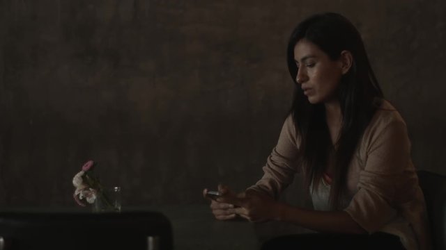 Young woman text messaging and waiting while sitting in bar