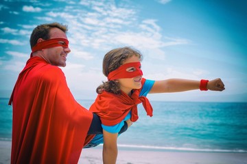 Happy father and son in superhero costume enjoying at beach