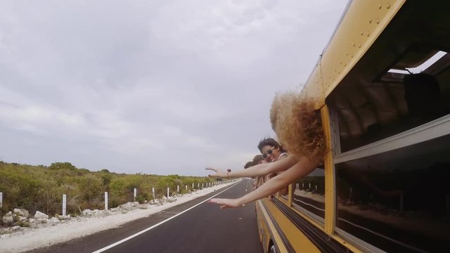 Friends hanging head out of bus window  enjoying