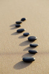 Fototapeta na wymiar set of hot stone on white sand calm beach in backbone shape. sel