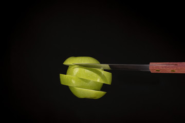 Knife , cut the apple into slices and black background .