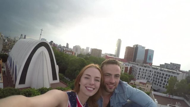 Young couple sitting on terrace and kissing  city in background