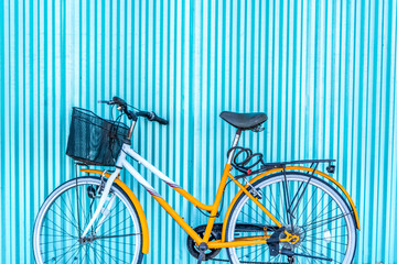 Bicycle with basket leaning against blue fence.