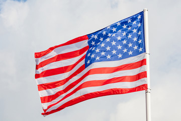 Obraz premium Close-up American flag waving against cloudy blue sky background