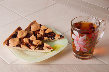 Cup of tea and plum cake with crumb on parchment paper