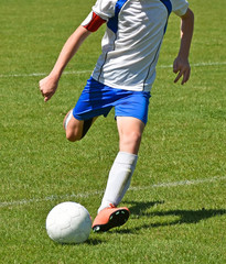 Young soccer player kicks the ball