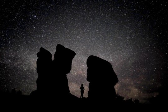 Naked woman silhouette against night sky with Milky Way, constellations and stars. Devil's Garden, Grand Staircase Escalante National Monument, Moab, Utah, USA. 
