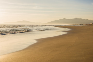 Fototapeta na wymiar Footsteps on a clear beach sand and a woman silhouette