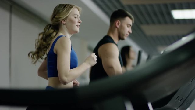 Pretty smiling blond woman running on treadmill