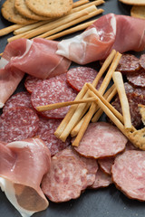 Assorted meat snacks, sausages on a blackboard, vertical