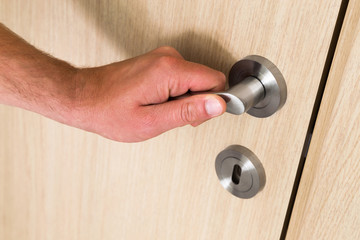Male hand opening a light wood interior door