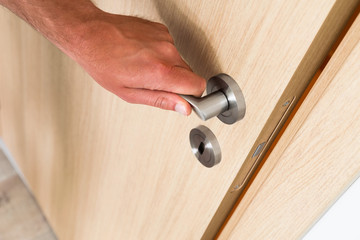 Fototapeta premium Man closing a light wood interior door