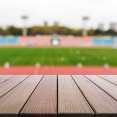 Wood table top on blur background of football field in stadium.
