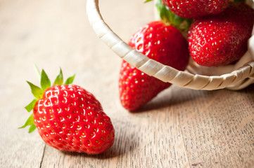 Fraises et petit panier en osier sur table en vieux bois