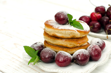 Pancakes with cherries, mint and powdered sugar