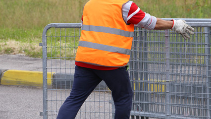 worker with high visibility reflective jacket moves iron hurdles