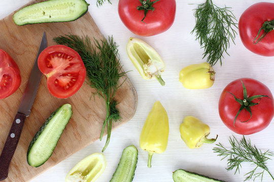sliced vegetables/ flat lay with green pepper, tomato, cucumber and dill with a knife and cutting board top view 