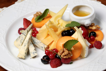 Plate of assorted cheese with berries and honey