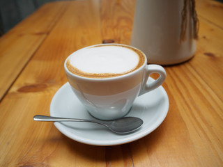 Cappuccino in a white cup on wooden background